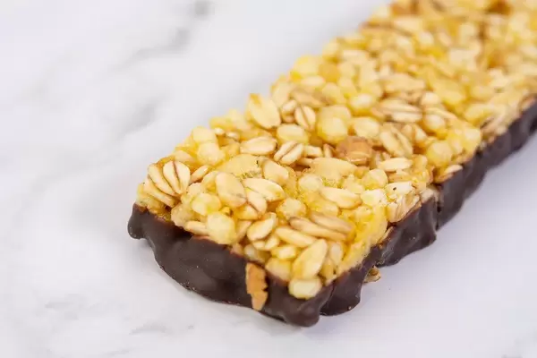 Antioxidant-Müsliriegel mit Orangengeschmack und Schokoladenüberzug, auf einem weißen Tisch