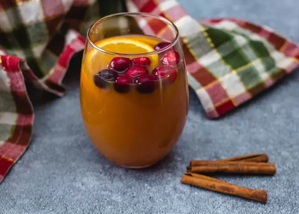 Apfelwein mit Orangenscheiben, Preiselbeeren und Zimtstangen
