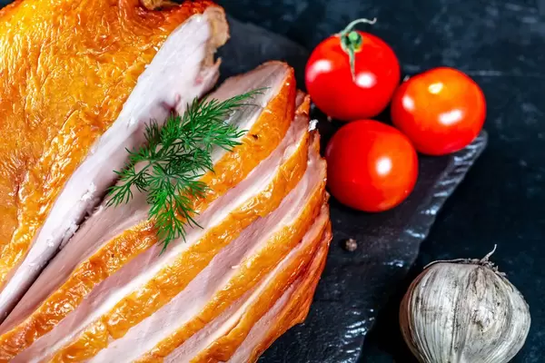 Appetitanregende Stücke geräuchertes Huhn mit Kirschtomatenknoblauch und -dill auf einem schwarzen Hintergrund