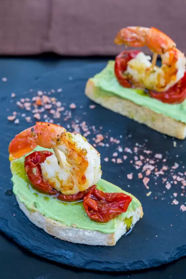Appetizer at Q11, Pollença: two slices of toasted bread with avocado, dried tomatoes, king prawns
