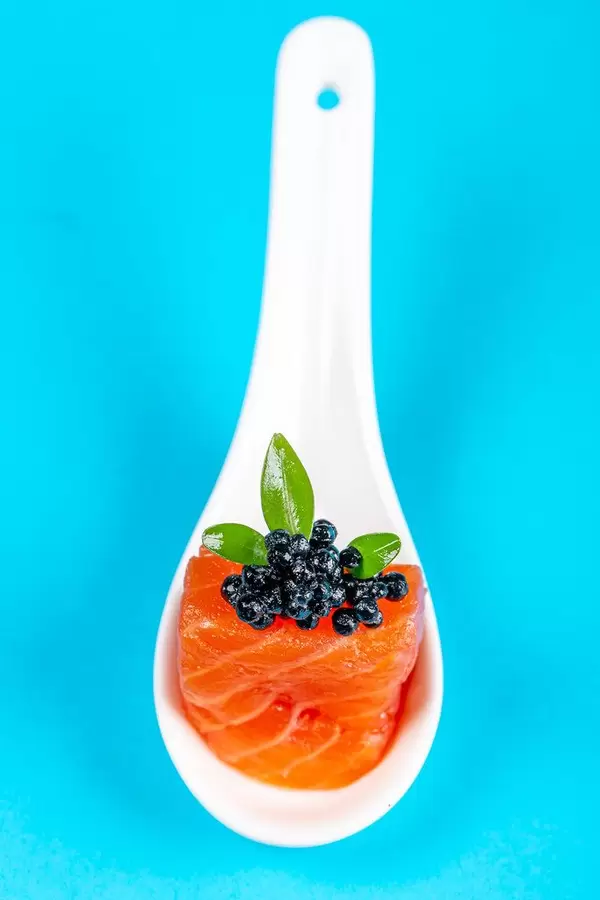 Appetizer of smoked salmon fillet and black caviar on a blue background