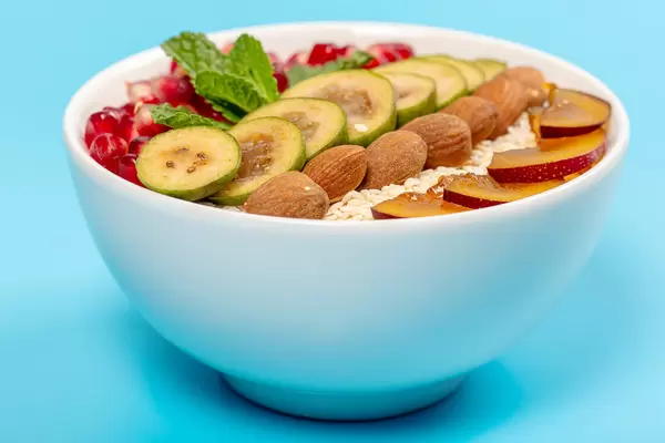 Appetizing oatmeal with fruits, almonds and mint on a blue background