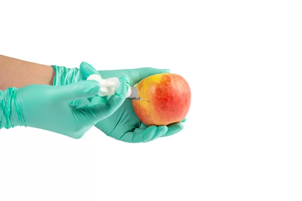 Apple in hand with rubber gloves and a syringe
