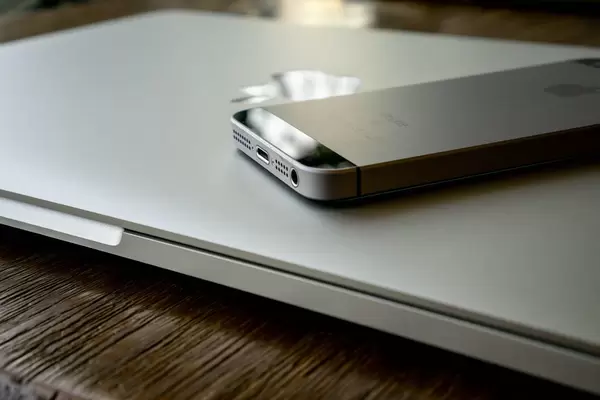 Apple iPhone auf MacBook Laptop auf Holztisch mit Reflektion