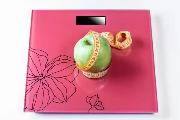 Apple umwickelt mit Maßband auf den Skalen als Symbol einer gesunden Ernährung