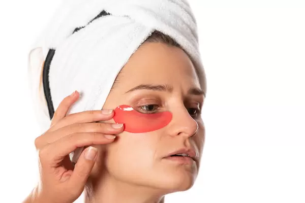 Applying a cosmetic patch under the eyes of a woman, close-up