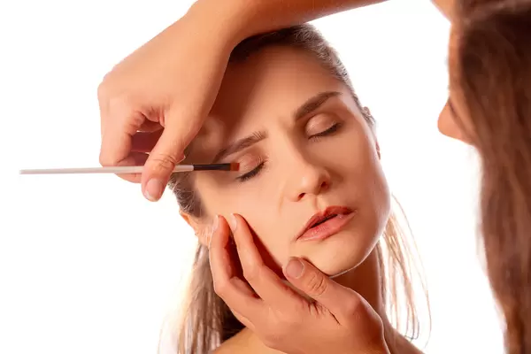 Applying eye makeup products on woman's face