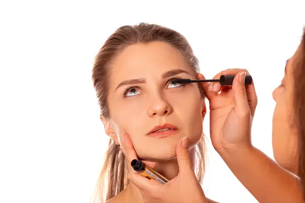 Applying mascara to a woman's eyelashes