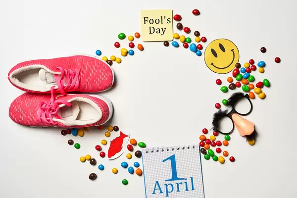 April fool's day surprise - shoelaces tied together, calendar, party mask and sweet candies on white background