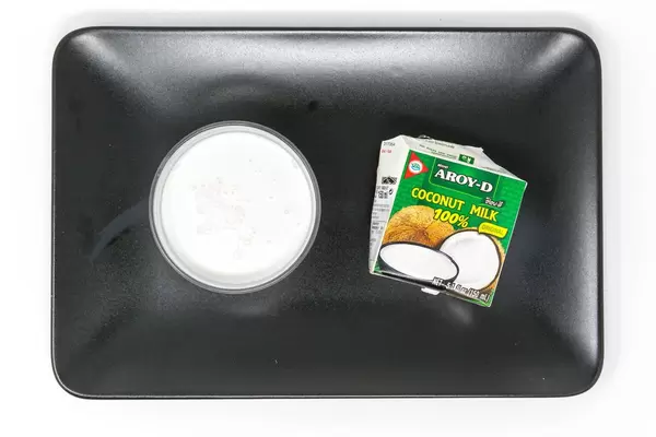 Aroy D - Kokosmilch von oben im Glas mit Verpackung - Aufsicht - Bildseite oben