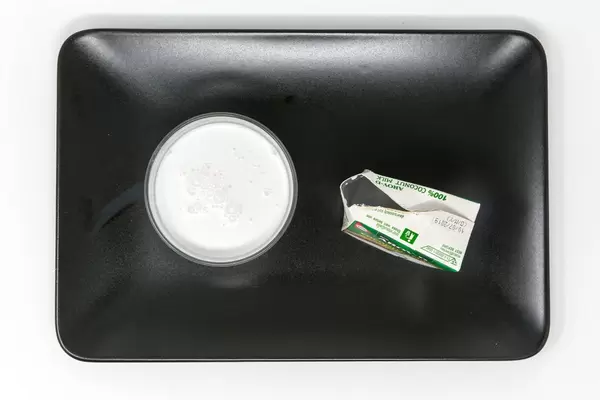 Aroy D - Kokosnussmilch im glas mit Verpackung auf schwarzem Teller - Aufsicht