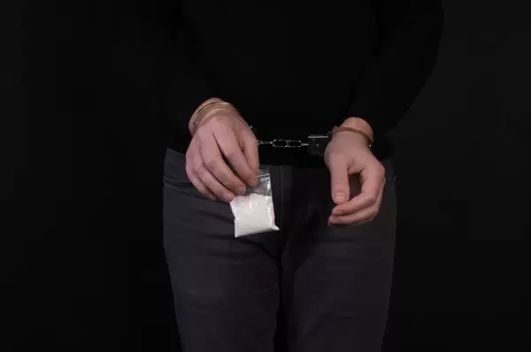 Arrested dealer holds a little bag of drugs