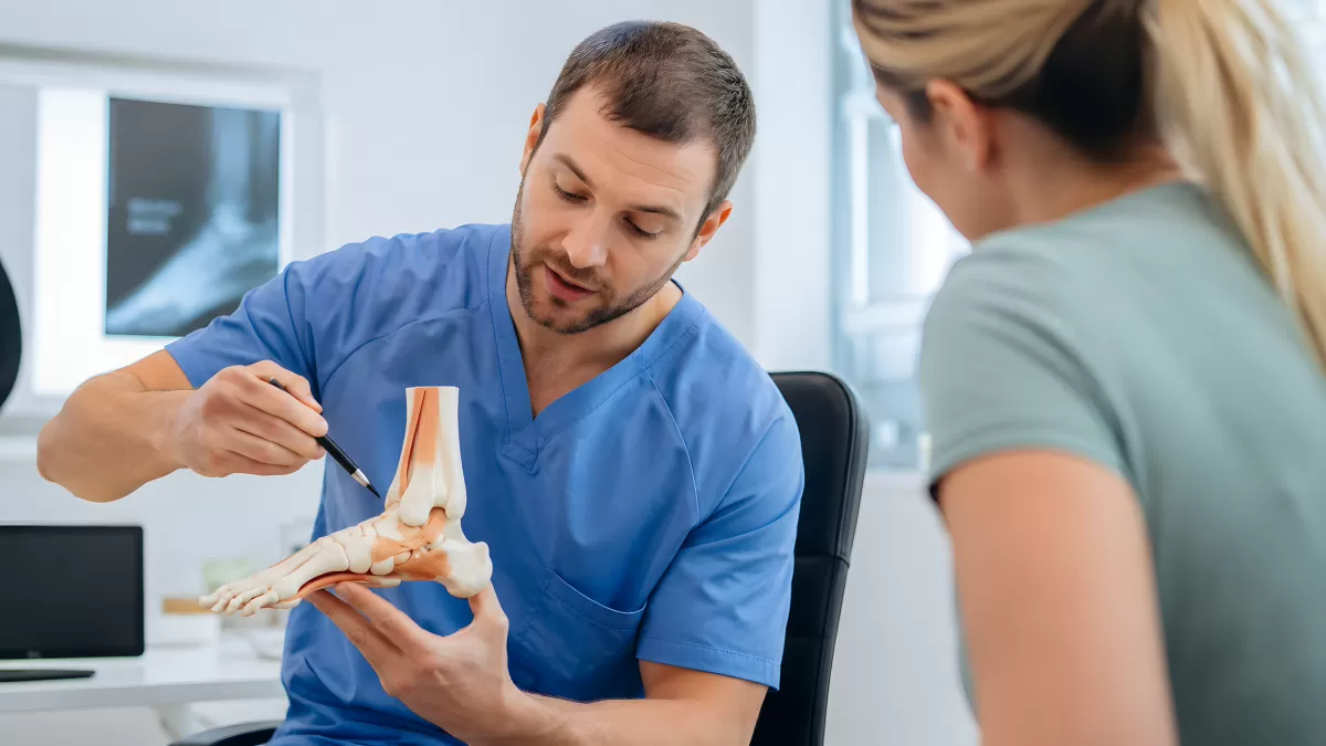 Arzt erklärt Patientin Fußanatomie am Modell