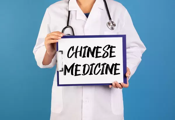 Arzt hält ein Schild mit der Schrift 'Chinese medicine' im blauen Hintergrund