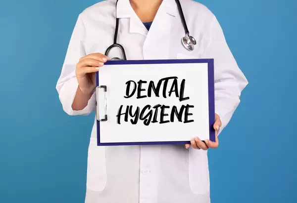 Arzt hält ein Schild mit der Schrift 'Dental Hygiene' im blauen Hintergrund