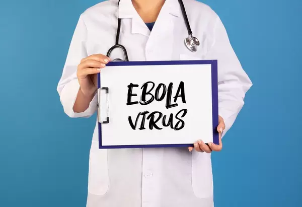 Arzt hält ein Schild mit der Schrift 'Ebola Virus' im blauen Hintergrund