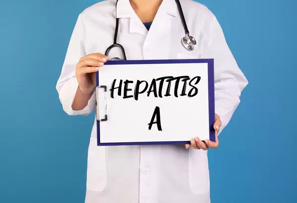 Arzt hält ein Schild mit der Schrift 'Hepatitis A' im blauen Hintergrund
