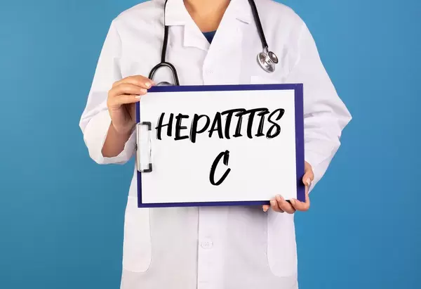 Arzt hält ein Schild mit der Schrift 'Hepatitis C' im blauen Hintergrund