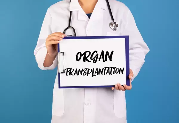 Arzt hält ein Schild mit der Schrift 'Organ Transplantation' im blauen Hintergrund