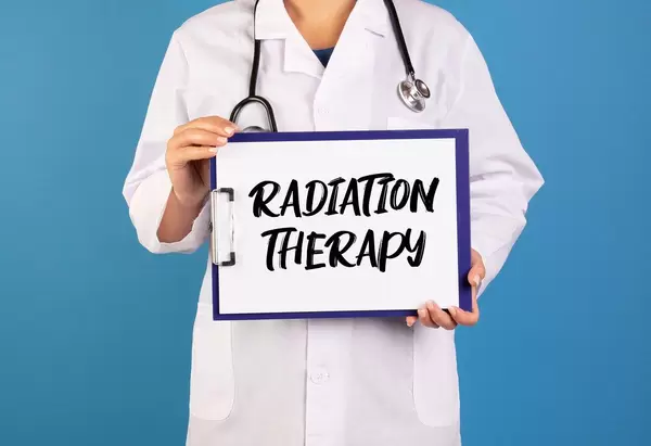 Arzt hält ein Schild mit der Schrift 'Radiation Therapy' im blauen Hintergrund