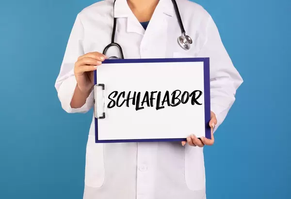 Arzt hält ein Schild mit der Schrift 'Schlaflabor' im blauen Hintergrund