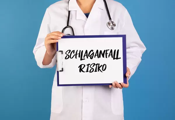 Arzt hält ein Schild mit der Schrift 'Schlaganfallrisiko' im blauen Hintergrund