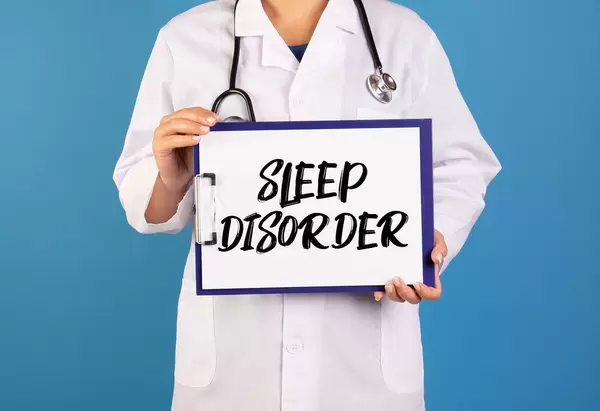 Arzt hält ein Schild mit der Schrift 'Sleep disorder' im blauen Hintergrund
