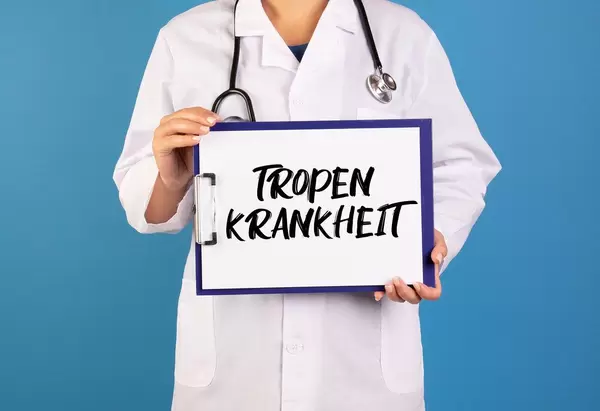 Arzt hält ein Schild mit der Schrift 'Tropenkrankheit' im blauen Hintergrund