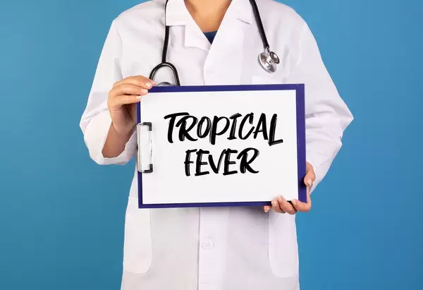 Arzt hält ein Schild mit der Schrift 'Tropical Fever' im blauen Hintergrund