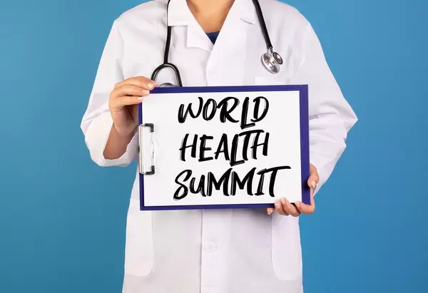 Arzt hält ein Schild mit der Schrift 'World Health Summit' im blauen Hintergrund