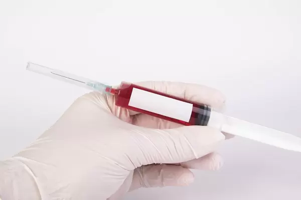 Arzt hält eine Blut-Spritze mit freiem Platz für Text