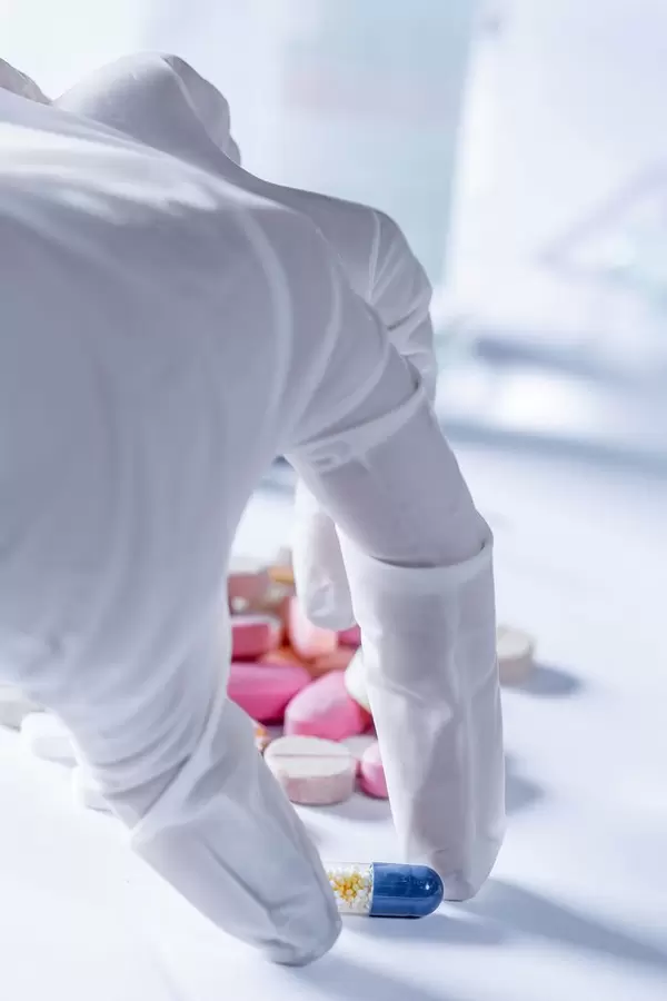 Arzt mit weißen Handschuhen nimmt Tablette aus Auswahl von Medikamenten