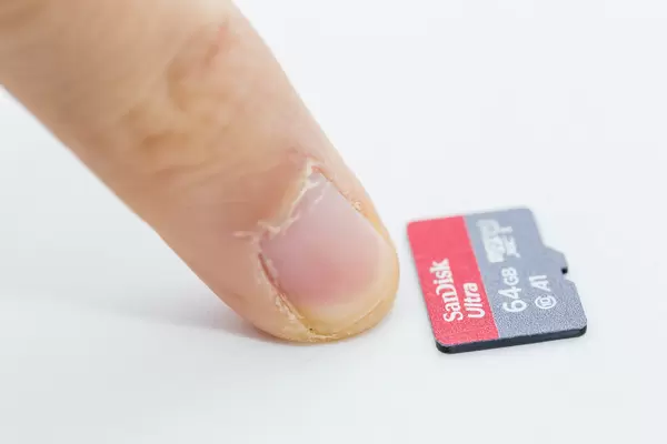 As small as a fingernail: close-up of Micro SD card SanDisk Ultra 64 GB on white background