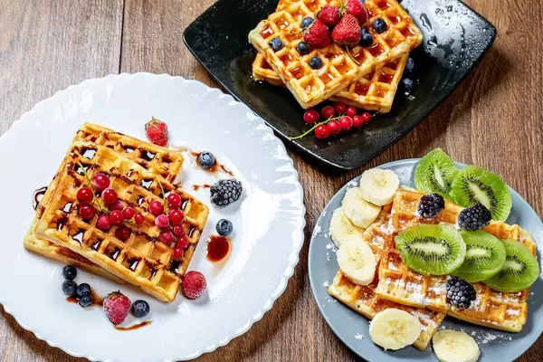 Assortment beautiful serve waffles with berries, fruits and syrups