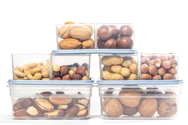 Assortment of different nuts in plastic containers on a white