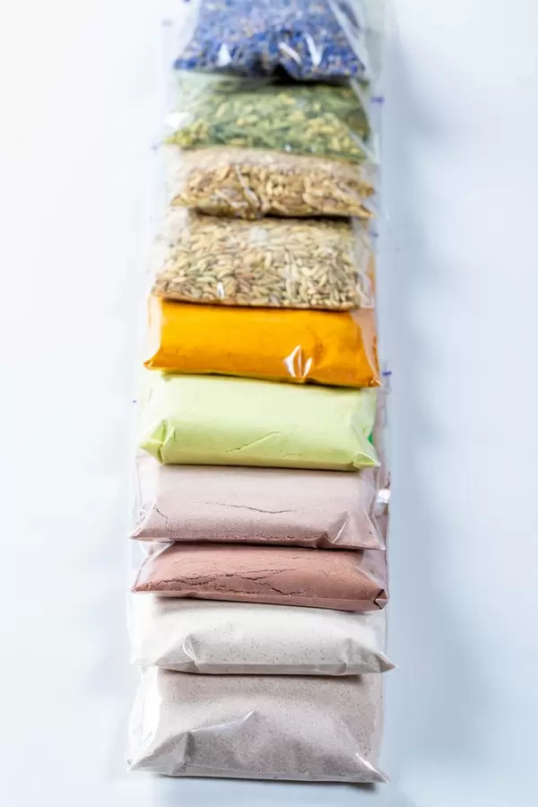 Assortment of dried flowers, leaves and petals in packages on white. Flat lay, top view