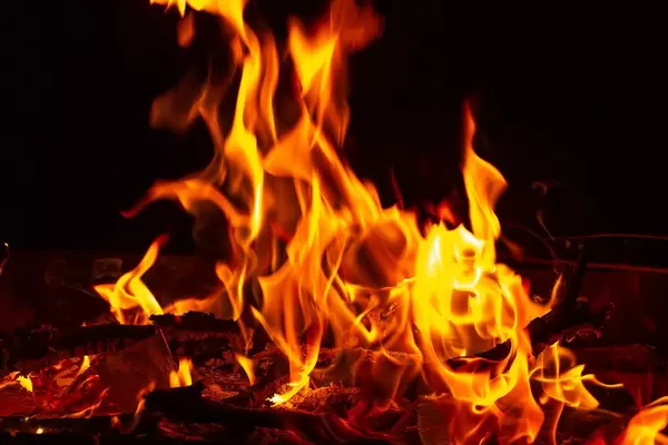 Äste und Papier liegen im Feuer mit hellen Flammen mit schwarzem Hintergrund