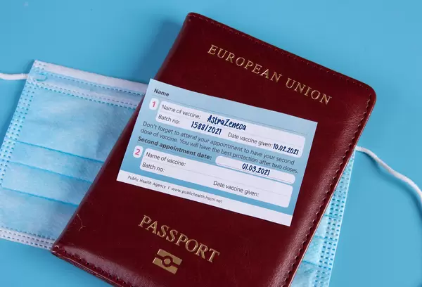 AstraZeneca Covid-19 vaccination certificate with passport and medical face mask