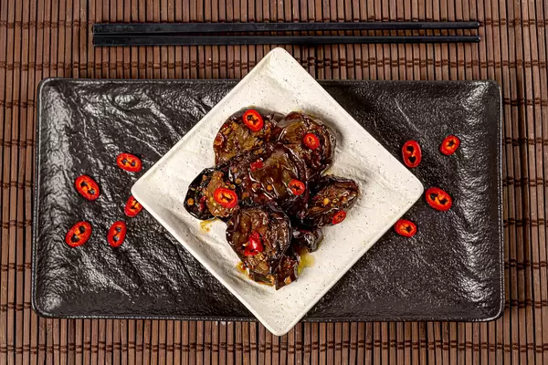 Aubergines with hot pepper on dark background, top view