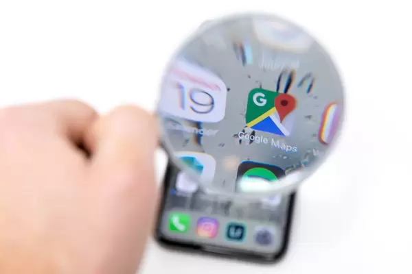 Auf Mobiltelefon durch Lupe betrachtetes Google Maps Icon neben Kalender App Logo