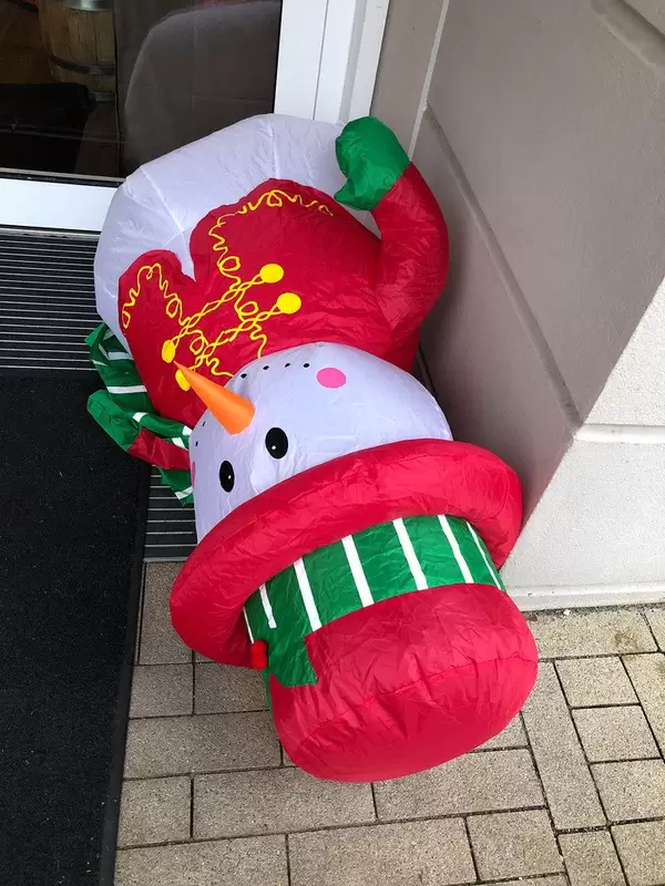 Aufblasbarer Schneemann liegt auf dem Boden vor der Haustür