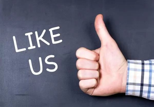 Aufforderung LIKE US in weiß auf schwarzem Untergrund neben Hand mit Daumen hoch