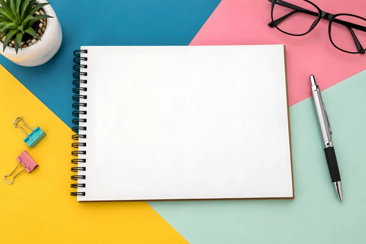 Aufgeschlagenes Notizbuch mit Stift auf buntem Hintergrund