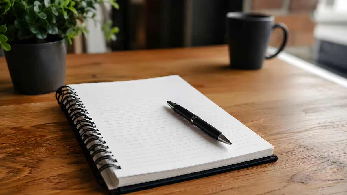 Aufgeschlagenes Notizbuch mit Stift auf Holztisch