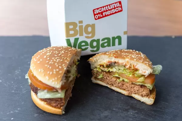 Aufgeschnittener Big Vegan TS Burger von McDonalds mit Bratling auf Soja- und Weizeneiweißbasis vor dem Verpackungskarton