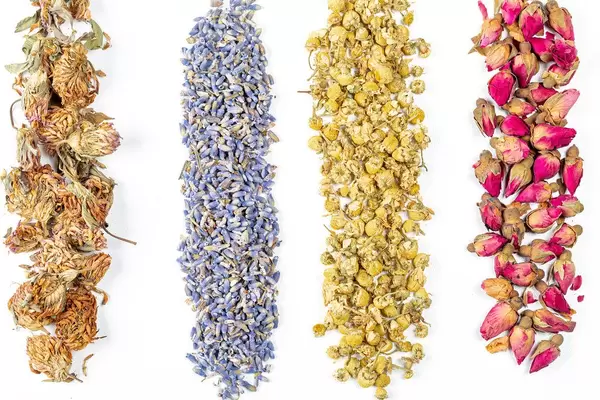 Aufnahme von oben: getrocknete Hibiskus-, Kamillen- und Lavendelblüten vor weißem Hintergrund