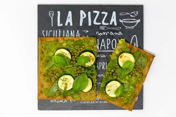 Aufsicht auf die grüne Lizza - eine Vegane Pizza mit Boden aus Chia und Leinsamen Zucchini, Erbsen, grünen Bohnen und frischem Basilikum