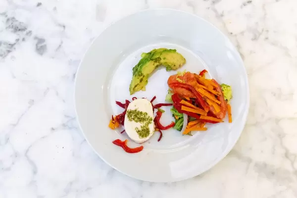 Aufsicht auf einen weißen Teller mit vegetarischer Gemüsespeiße mit Avocado und Mozzarella