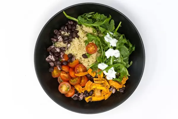 Aufsicht auf vegane Mahlzeit - Hello Fresh Kubanische Quinoa Bowl - mit Rucola mit Sauerrahm, schwarzen Bohnen, Kirschtomaten und zimtigen Süßkartoffeln
