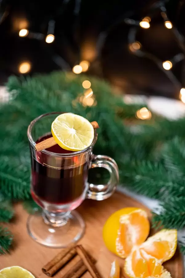 Aufsicht - Ein Glas Glühwein mit Zimtstange und einer Scheibe Zitrone  und Tannenzweigen im Hintergrund